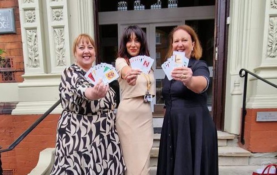 Photo of Police & Crime Commissioner Henry, ISVA & SSS Manager and the Attorney General holding up cards from the A-Z of Consent